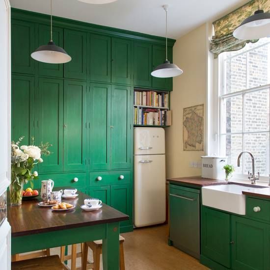 a pretty emerald kitchen with dark stained wooden countertops, pendant lamps and printed shades