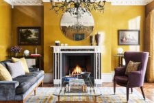 a quirky modern living room with mustard walls, a fireplace, a beautiful statement chandelier and elegant furniture