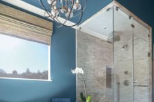a royal blue painted bathroom with a neutral shower space,a  tub and a vintage chandelier