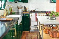 a shiny glam emerald kitchen, a white subway tile backsplash, black countertops and gold and brass touches