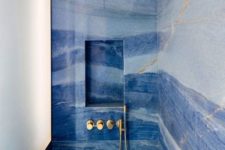 a shower space done with blue marble tiles and touches of gold looks just jar-dropping