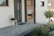 a simple and modern porch with a wood slab screen and a white chair planter looks cool and stylish