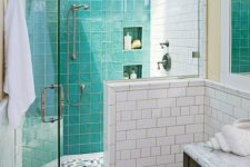 a small modern bathroom in neutrals, with turquoise tiles in the shower, a skylight and two types of white tiles