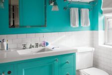 a small modern bathroom with turquoise walls, white subway tiles, a turquoise vanity and white appliances