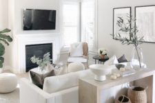 a small neutral living space with a white sofa and chairs, a built-in fireplace, a console and some accessories