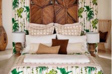 a statement boho tropical bedroom with a wooden carved screen, a platform bed, wooden lamps and printed bedding
