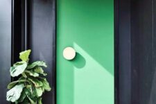 a stylish and statement-like porch with black planked walls, an apple green statement door with a knob and a catchy planter with a large green plant