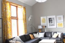 a stylish bright living room with grey walls, a black sectional, yellow printed textiles and a bold gallery wall