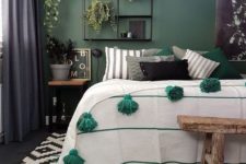 a stylish eclectic bedroom with a green accent wall, wooden and metal furniture, a woven pendant lamp and touches of green textiles