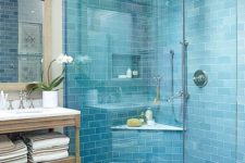 a stylish light blue bathroom clad with subway tiles, a vintage wooden vanity and a mirror in a wooden frame