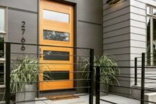 a stylish modern entrance with grey walls, a glass insert stained door, grey planters with greenery that features a lot of texture
