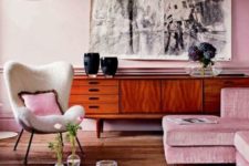 a stylish modern living room with light pink walls and a matching sofa, a graphic artwork and a rich toned credenza