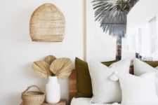a super neutral tropical bedroom with wooden and plywood furniture, a tropical artwork and wicker touches and dried fronds