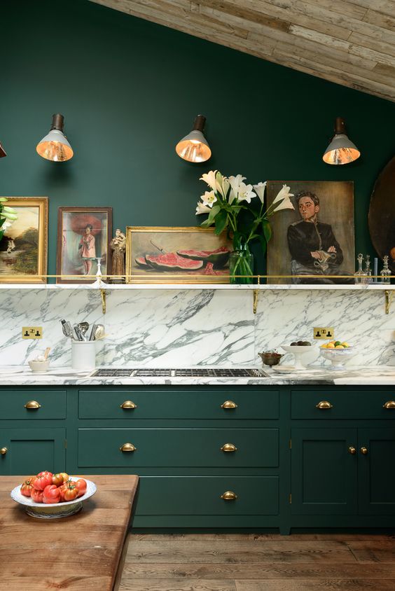 a very elegant and chic vintage kitchen in hunter green, with a white marble backsplash and touches of gold