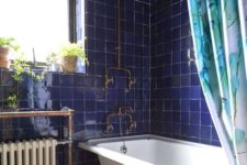 a vintage-inspired bathroom with bold blue Zellige tiles, a vintage radiator and bathtub, brass touches