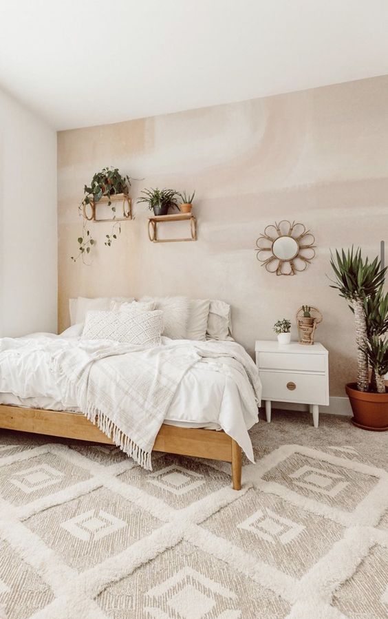 a warm neutral bedroom with an accent pastel wall, a wooden bed, a white nightstand, lots of potted plants