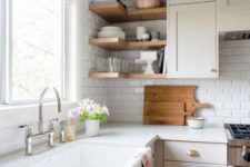 a warm neutral kitchen with white subway tiles, white countertops, touches of brass and built-in shelves