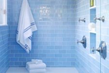 a watery blue bathroom fully clad with tiles and touches of neutral metallics for a chic and shiny look