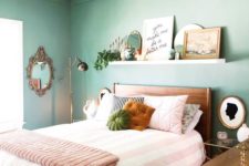 a welcoming bedroom with green walls, wooden furniture, a ledge as a gallery wall and gold and brass lamps
