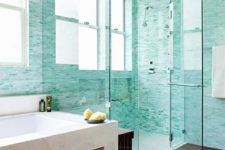 a welcoming modern bathroom with neutral stone, turquoise tiles, a dark wooden slab, several windows for much natural light
