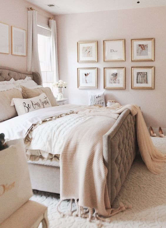 a welcoming neutral bedroom with blush walls, a grey upholstered bed, a gallery wall and soft layered bedding