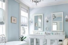 a white bathroom with pale blue walls, a mirrored vanity, and a herringbone tile floor pattern
