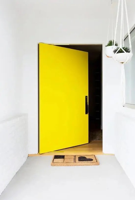 a white entrance with a concrete floor and an oversized yellow square pivot front door are amazing to highlight the exterior of your home