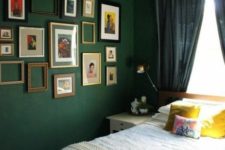 an eclectic bedroom with dark green walls and a ceiling, navy curtains, a gallery wall and bright bedding