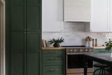 an eclectic kitchen in hunter green, with white upper cabinets and a subway tile backsplash and a white hood