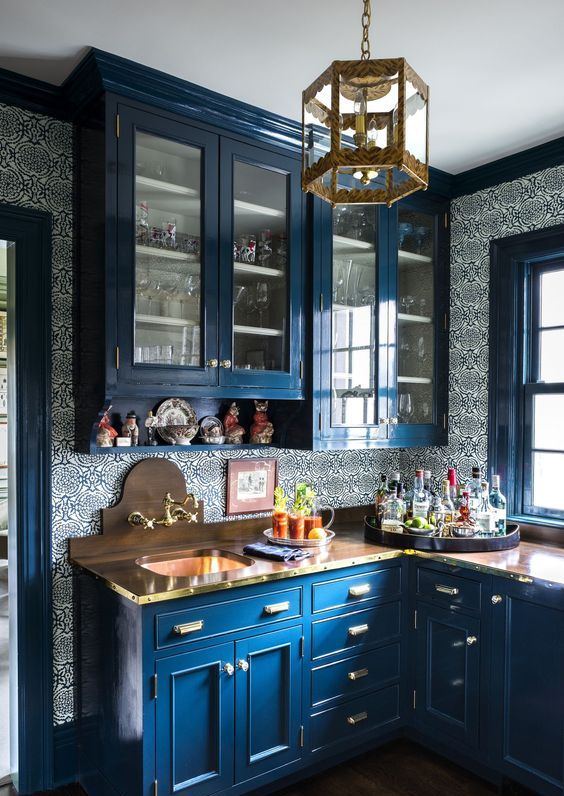 an exquisite kitchen in classic blue, with a patterned tile backsplash, wooden countertops and a gold pendant lamp