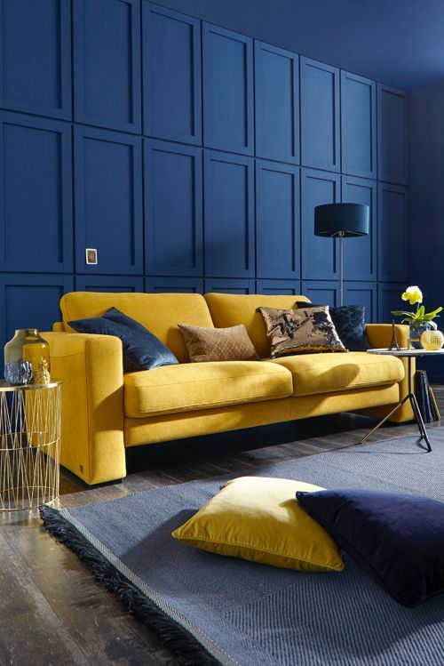 an extra bold blue living room with a paneled wall, a mustard sofa and matching textiles looks wow