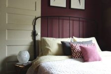 06 a refined vintage bedroom with plum-colored walls, a black forged bed, colorful printed bedding and cute artworks