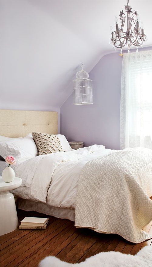 a romantic and inspiring lilac bedroom with a tan bed, neutral catchy bedding, a blush floral chandelier and a white nightstand