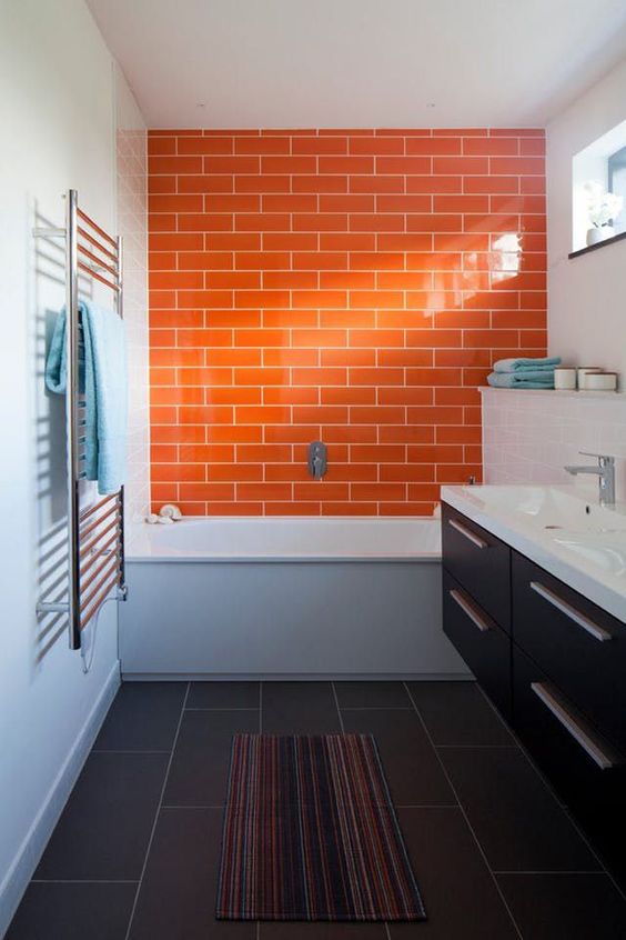 a stylish modern bathroom with an orange tile accent wall, a dark brown vanity and white appliances