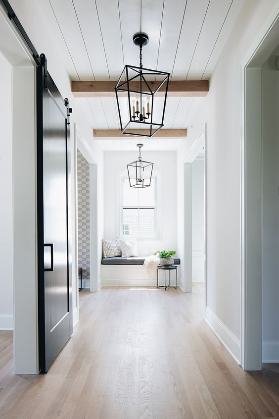 a corridor with a reading nook by the window lit up with light wooden floors and natural light, too
