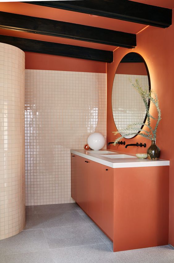 a creative bathroom in burnt orange and creamy, with tiles and matte surfaces and black wooden beams