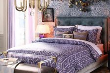 19 a maximalist bedroom with a printed accent wall, a bold artwork, a glam chandelier and a bench with gold touches and lilac and purple linens