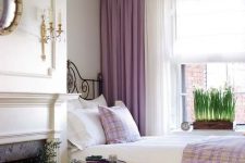 21 a sophisticated bedroom in neutrals, with a chic chandelier, a non-working fireplace, potted blooms and touches of lilac and purple