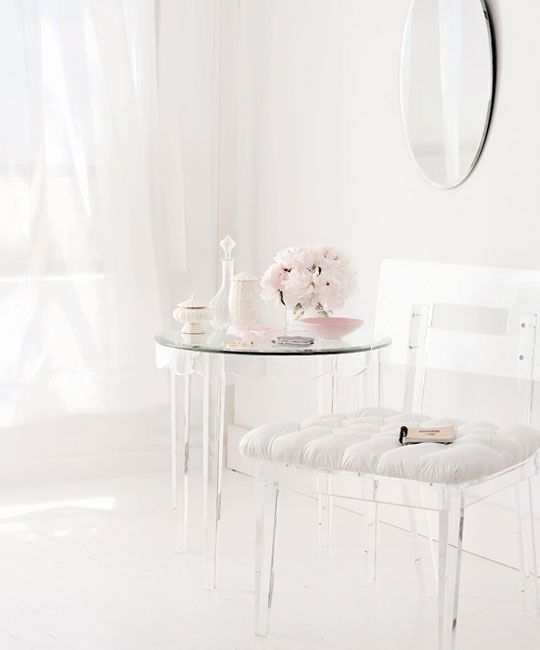 a lucite chair with a white upholstered seat and a table with lucite legs for a feeling of lightness