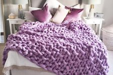 25 a white and grey bedroom with elegant and simple furniture and lamps and gorgeous purple pillows and a chunky knit blanket