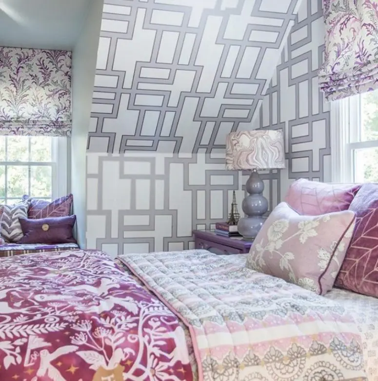 a white, grey and lilac bedroom with prined wallpaper, floral curtains, pink and lilac textiles is romantic and pretty