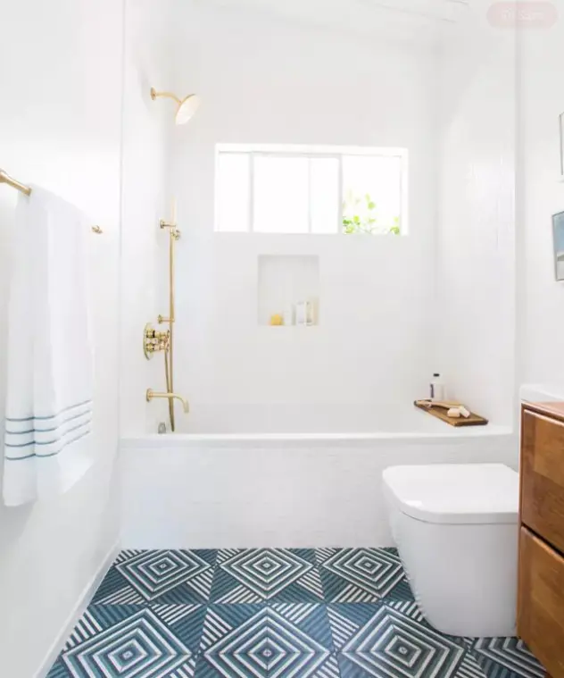 a beachy bathroom with white tiles, a blue geo tile floor, white appliances, a timber vanity and gold fixtures