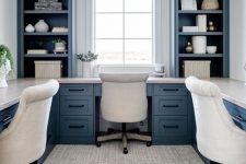 a beautiful blue and white home office with a long shared desk that goes along all the walls and stylish storage units by the window
