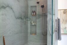 a blue stone shower space with a niche for storage, blue towels and touches of wood