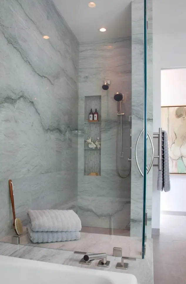 a blue stone shower space with a niche for storage, blue towels and touches of wood
