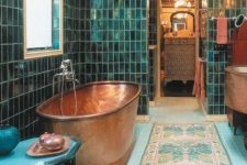 a bold Moroccan-inspired bathroom clad with green and blue tiles, a copper bathtub and refined furniture