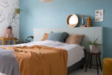 a bold contemporary bedorom with a blue accent wall, a grey headboard, a woven lamp and catchy bedding