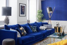a bold mid-century modern living room with a bright fabric wlal, white panels, an electric blue sofa and a bold yellow chair