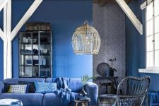 a bold monochromatic living room with bold blue walls, a matching sofa and chair plus matching textiles