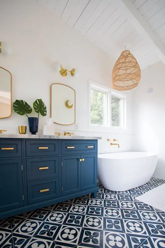 a bold nautical bathroom with white walls, navy and white printed tiles, a navy vanity with sinks, an oval tub and a woven pendant lamp